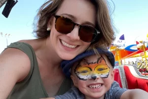 Mother and child enjoying a day at the fair, child with face painted like a tiger, symbolizing joy in everyday life while securing passive income from home.