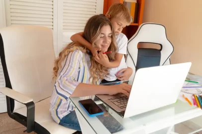 Stay at home mom working on a laptop with her young son hugging her, representing the best side hustles for stay at home moms.