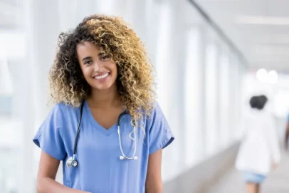 Smiling nurse in scrubs with a stethoscope around her neck — representing confidence, balance, and opportunity tied to the best side hustles for nurses.