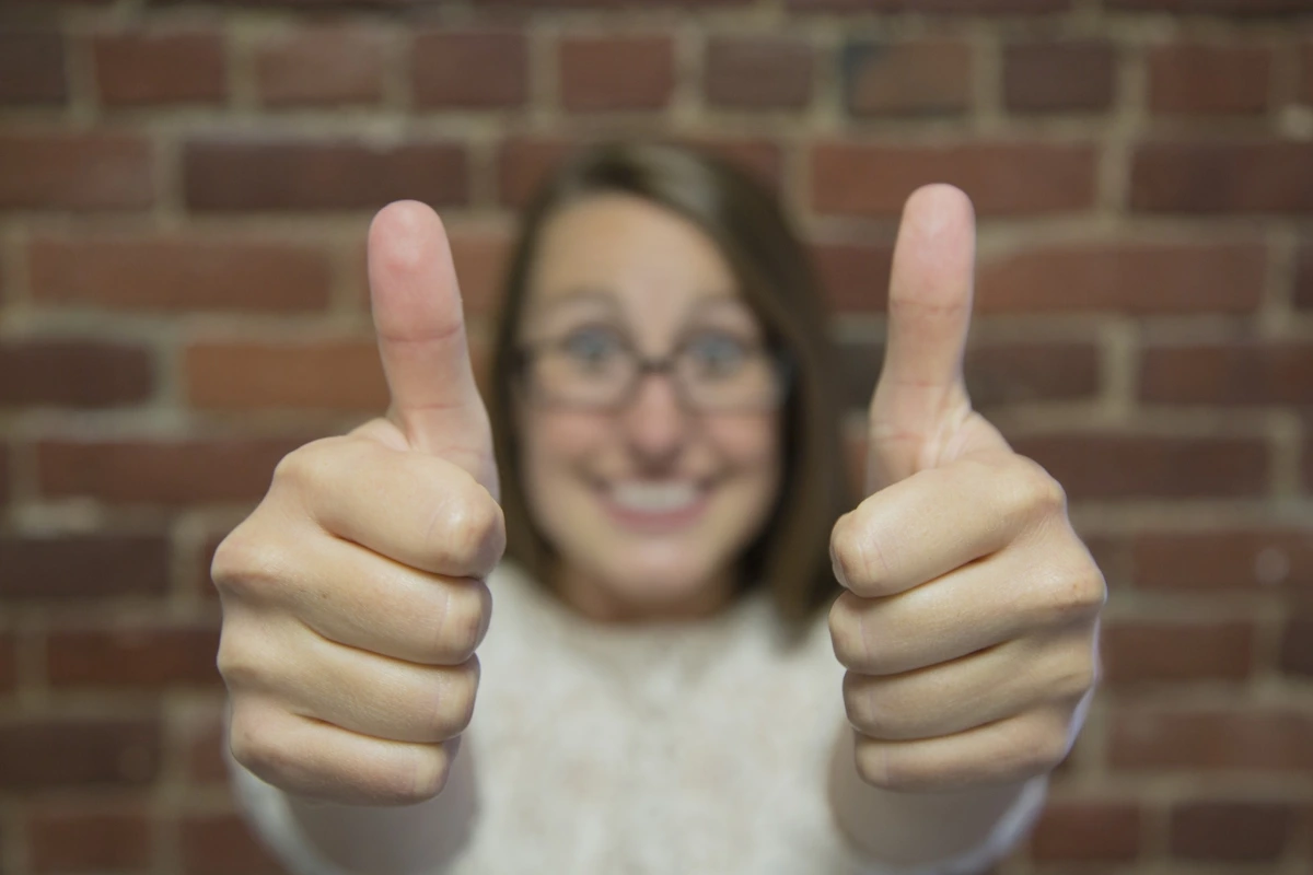 Smiling woman giving two thumbs up, representing excitement and success from finding good side hustles.