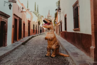 Person in a dinosaur costume standing on a cobblestone street symbolizing creative ways to increase income.