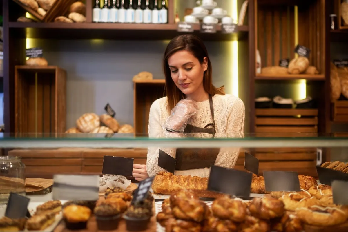 A female entrepreneur running a bakery, showcasing fresh bread and pastries — an example of how to start businesses that actually succeed.