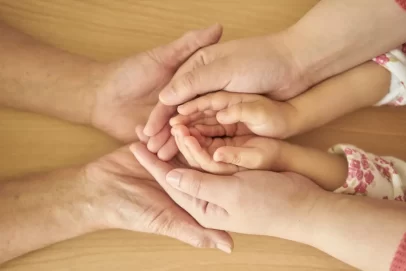 Close-up of three generations’ hands gently stacked together, symbolizing family legacy and long-term financial security — perfect for illustrating 7 Everyday Money Rituals That Quietly Build Generational Wealth Now.
