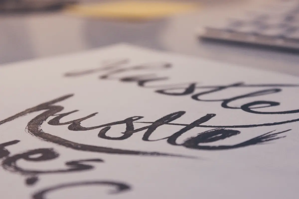 Close-up of the word “hustle” written in bold brush lettering on paper, symbolizing motivation and ambition — perfect for an article titled Do You Know How to Create a Passive Side Hustle.