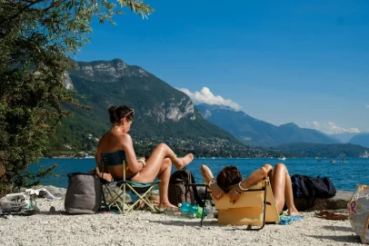 Two people relaxing on chairs by a scenic mountain lake under a bright blue sky, symbolizing financial freedom and early retirement — perfect for illustrating Retire Early With This Surprisingly Easy Math Trick.