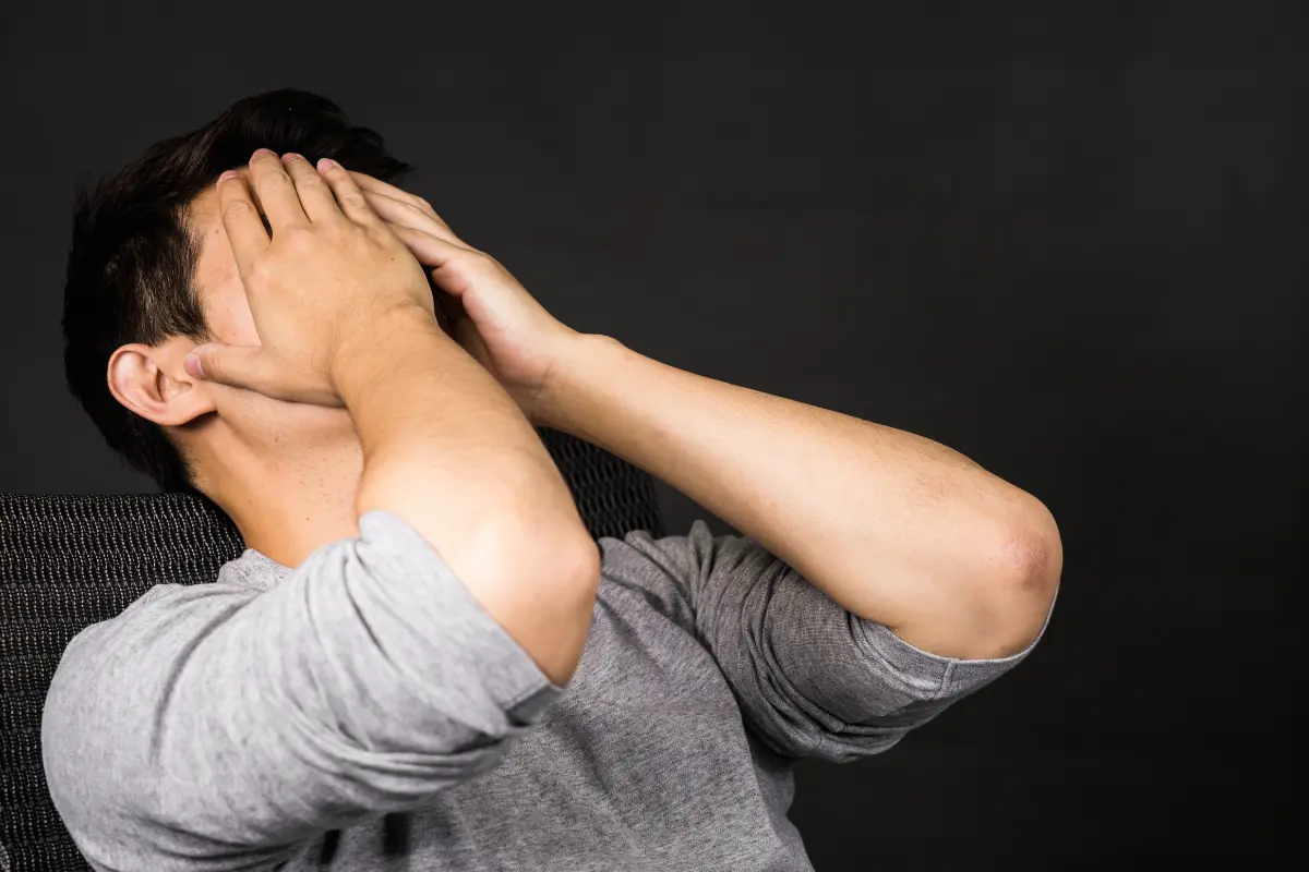 A stressed man covering his face with his hands, symbolizing frustration from common investing mistakes.
