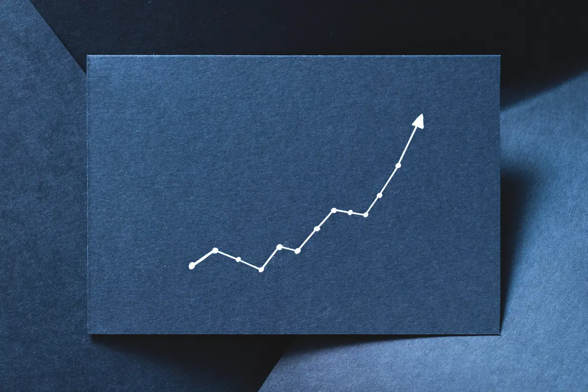 White upward-trending line graph on a dark blue background, symbolizing steady financial growth through small daily savings.