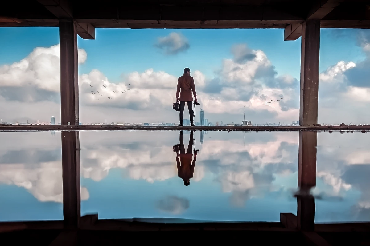 A person standing alone in an open structure overlooking a city skyline, reflecting on decisions that make you rich and long-term success.