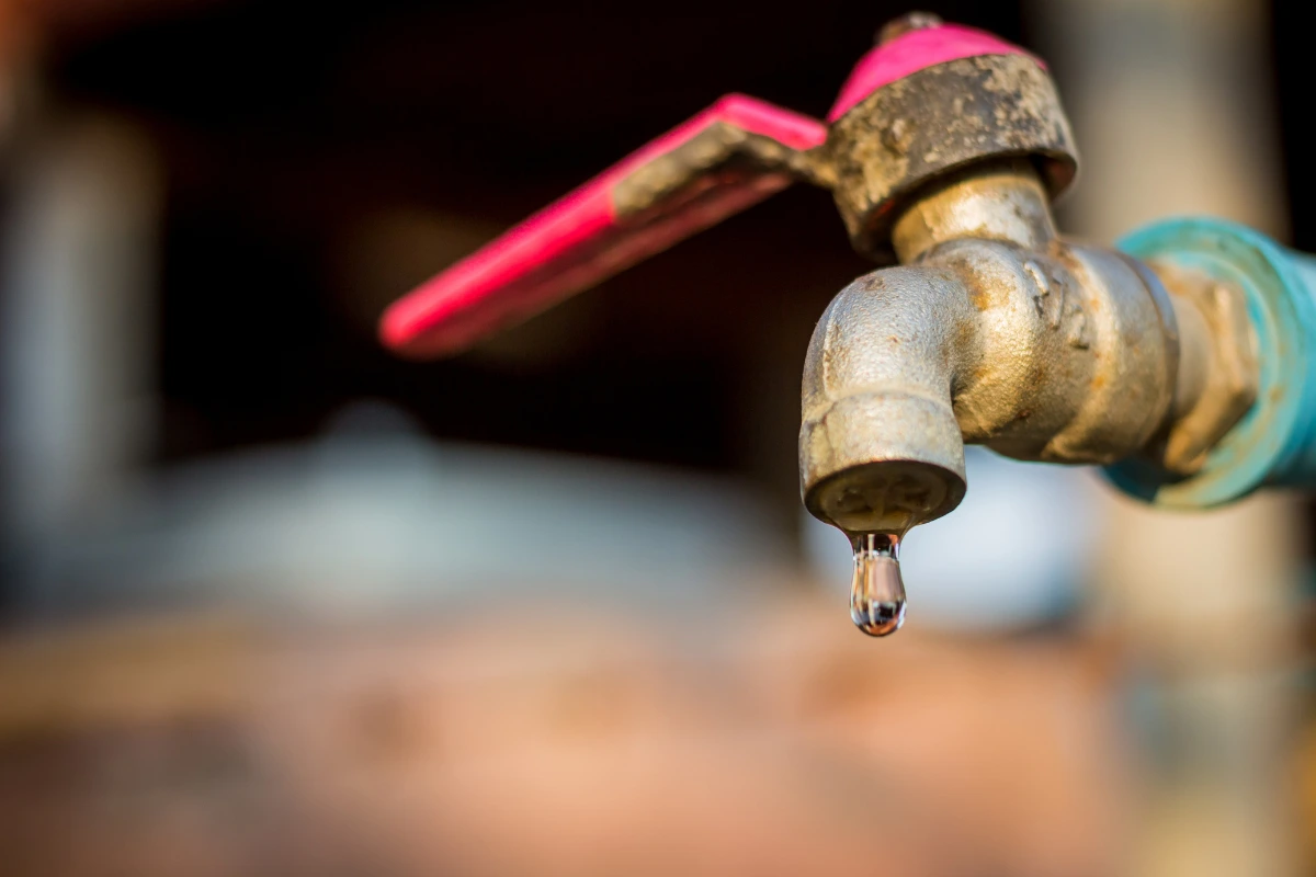 Dripping outdoor faucet symbolizing money leaks and small expenses adding up over time.