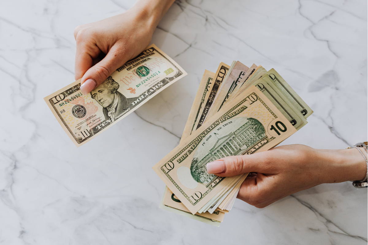 Hands counting U.S. cash on a marble surface, representing smart money moves, budgeting, saving, and building wealth.